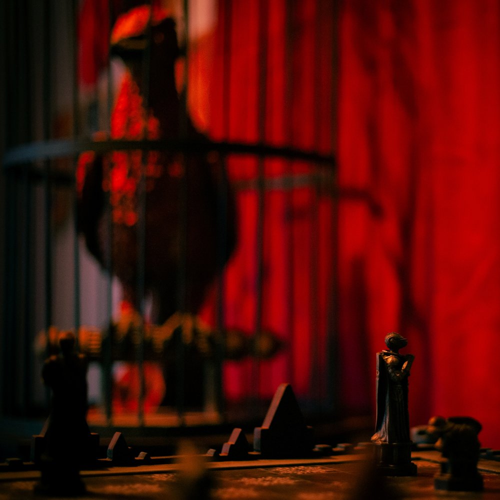 Figurki magicznych szachów, w tle feniks w klatce – pokój zagadek Powrót czarnoksiężnika, escape room Keyword Warszawa
